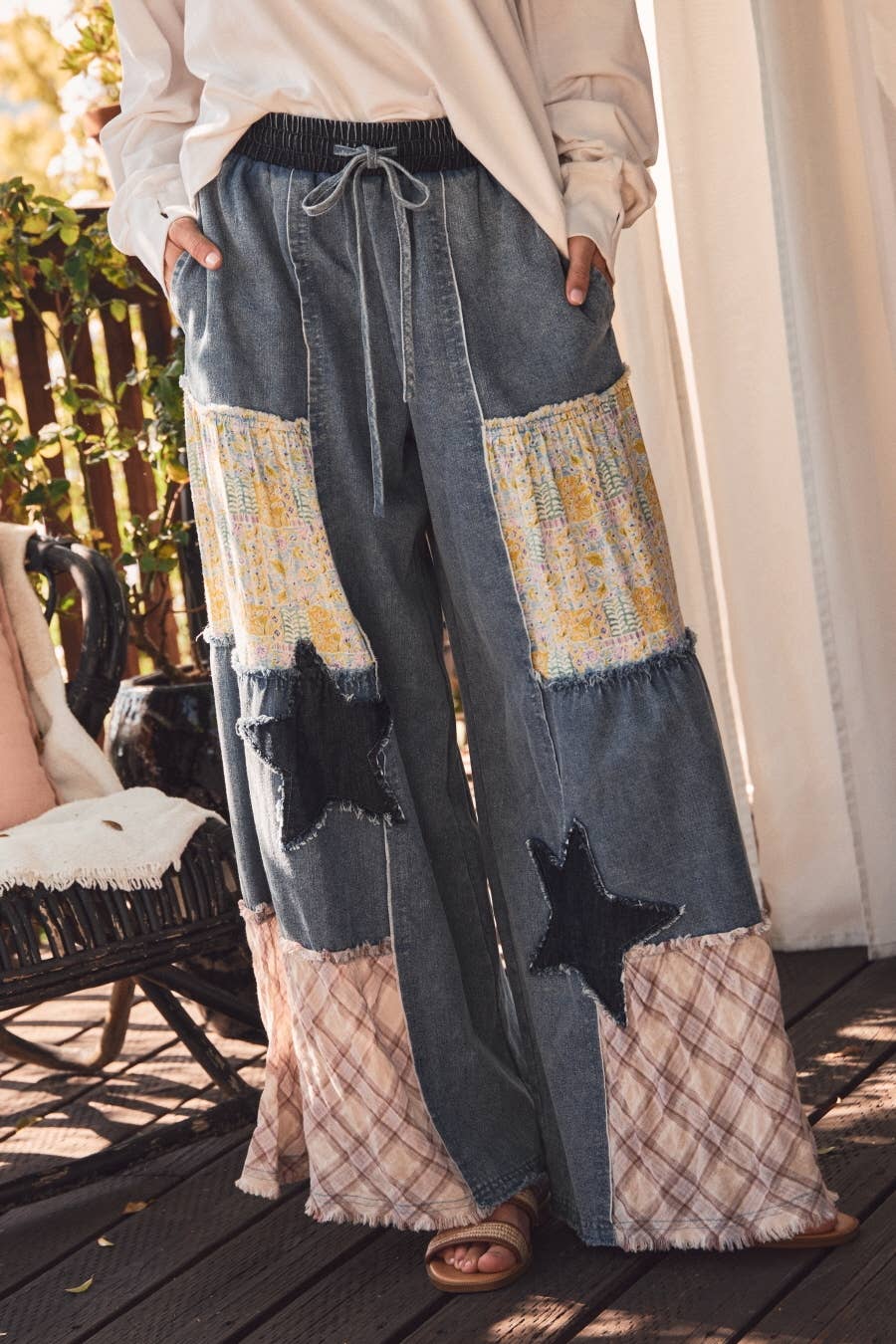 Close up of Plus size mixed fabric patchwork wide leg pants in washed denim with lace inserts, star appliqué, and drawstring waist — boho-luxe women's pants by Spirit & Wind Boutique