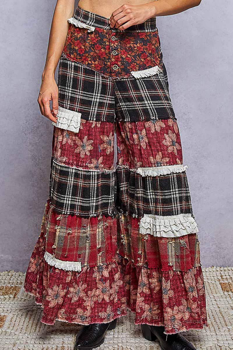 A high-waisted, tiered maxi skirt with a patchwork design of red floral prints, black plaid, and white lace ruffles, shown on a model.
