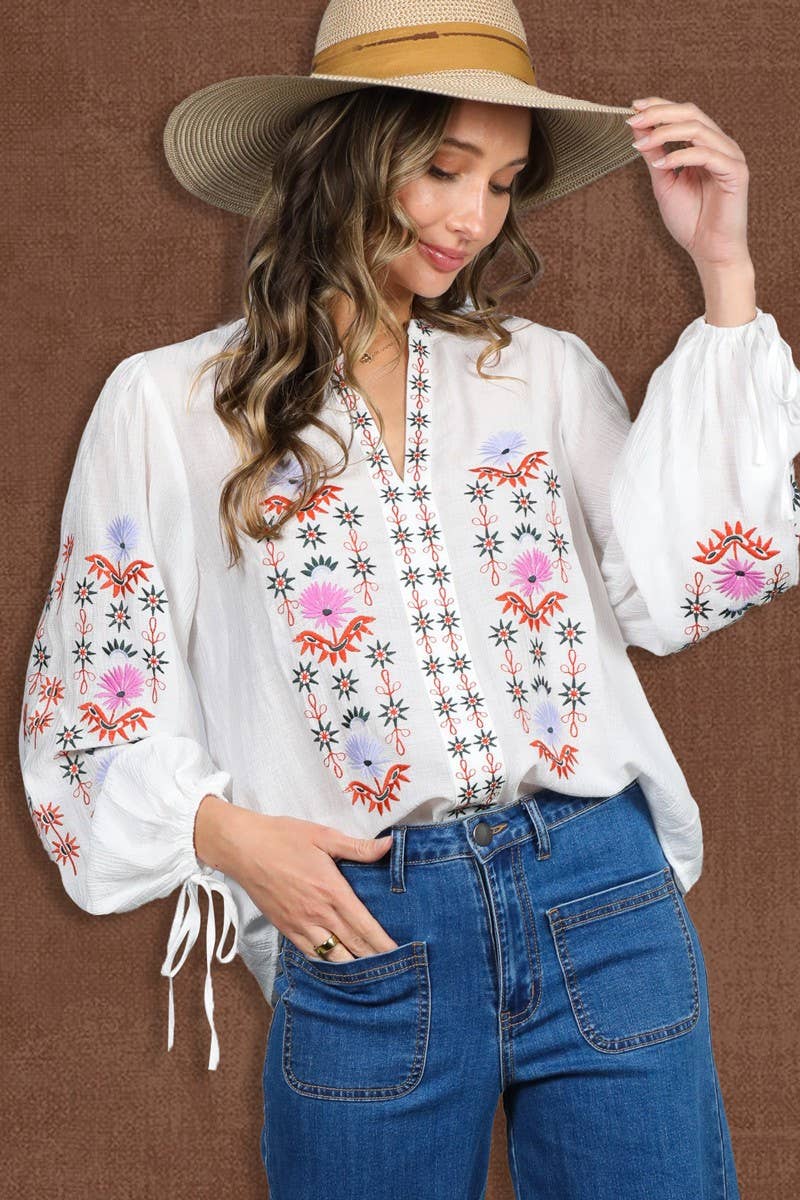 White embroidered peasant blouse with multicolor floral front, split V-neck, and balloon sleeves with ties