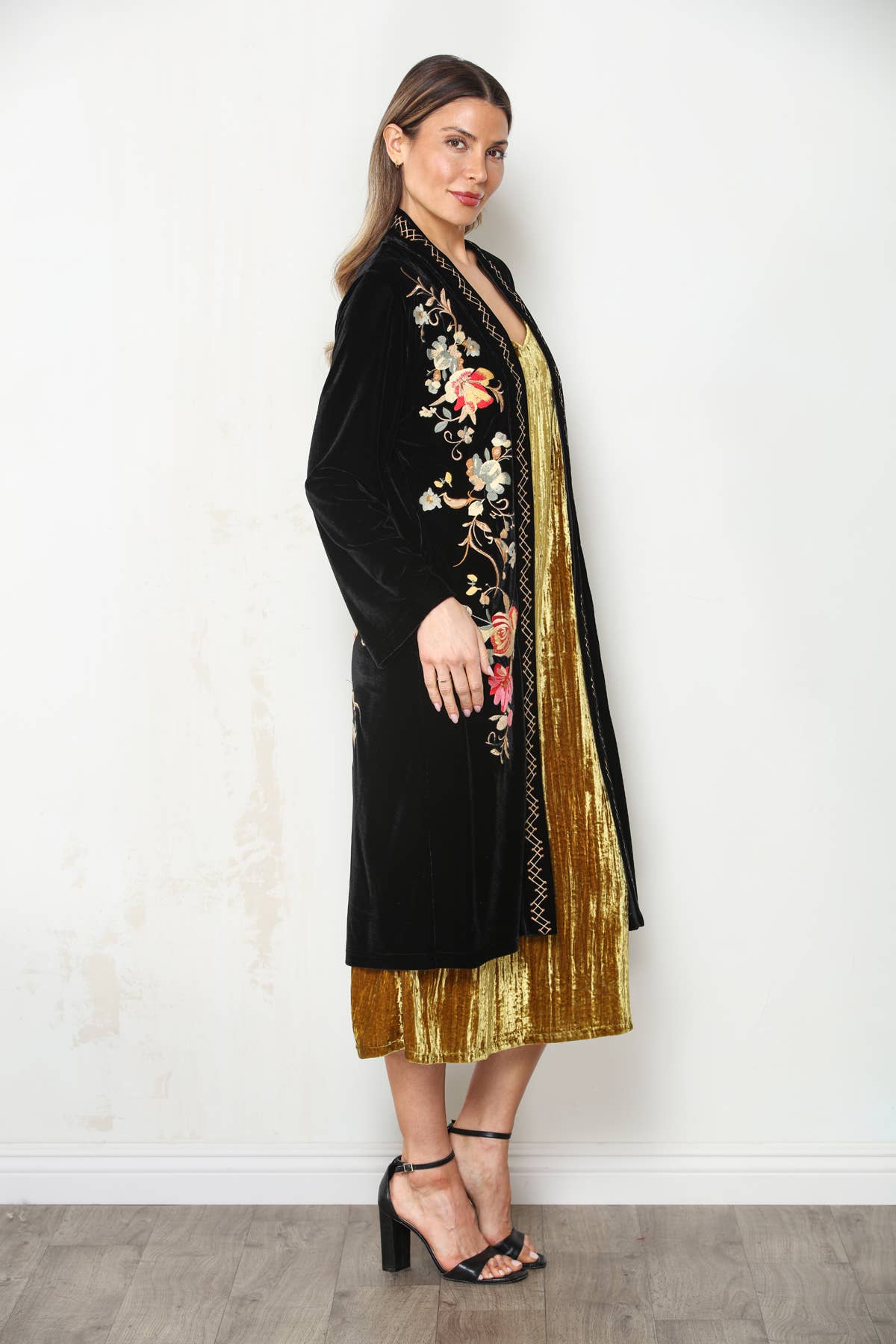 Three-quarter front view of black velvet duster showing floral embroidery and geometric stitched open-front trim.