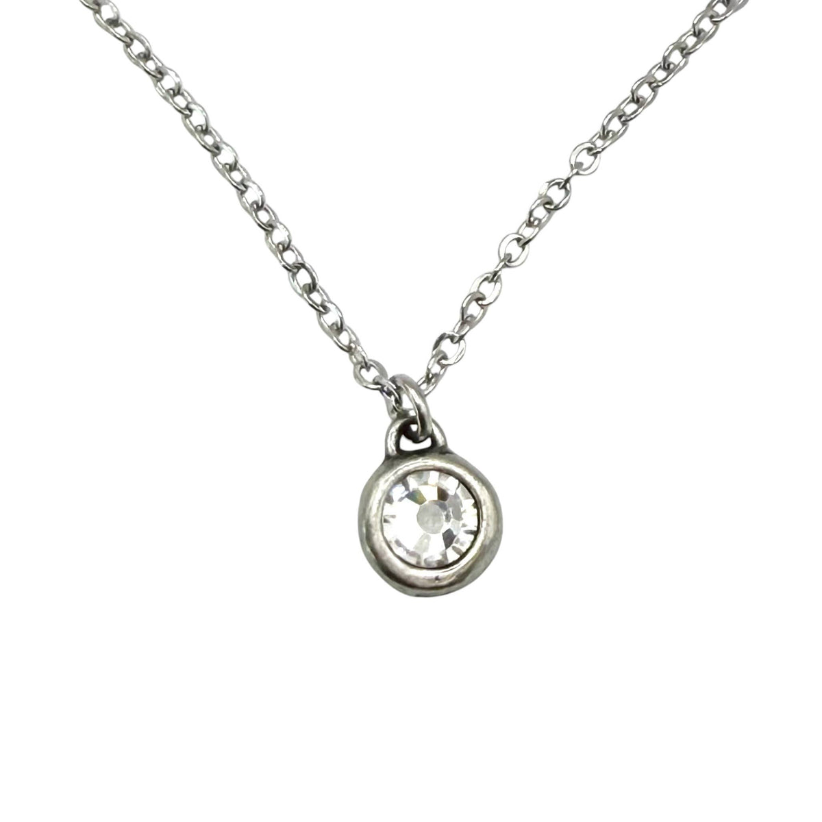 A silver chain necklace with a small round bezel-set clear crystal pendant, shown against a plain white background.