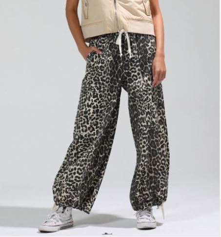 Person wearing leopard print pants on a plain background