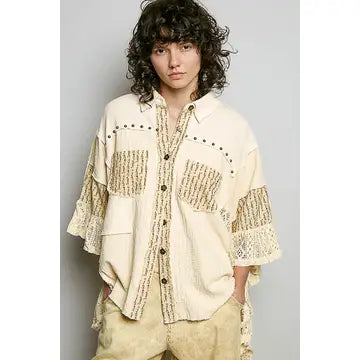 Crochet Lace Ruffle Gauze Shirt in Cream – front view, oversized button-down with crochet lace patch pockets, stud trim, and tiered ruffle sleeves, styled with khaki wide-leg pants