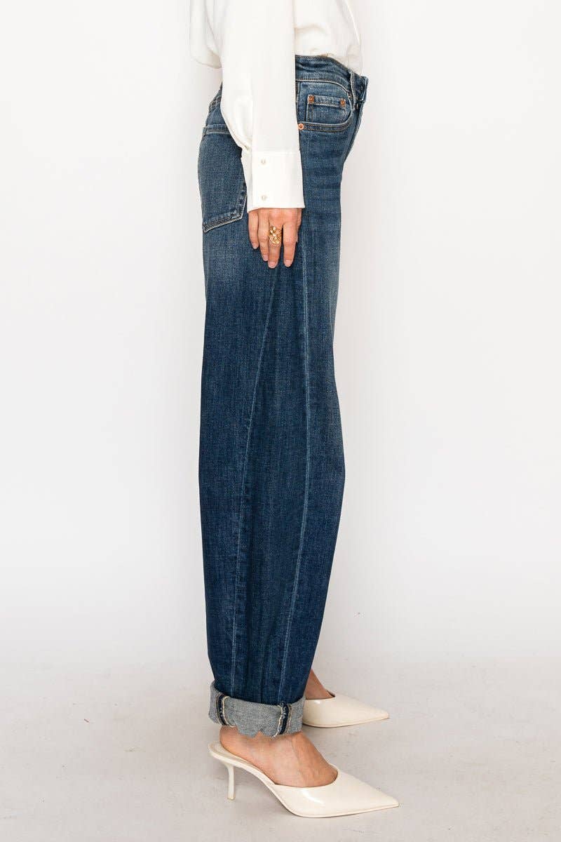 Person wearing blue jeans and white shoes on a plain background