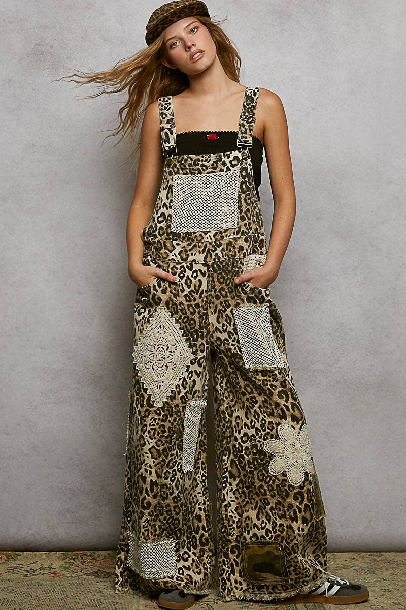Boho leopard print patchwork overalls featuring wide legs, crochet lace appliqué details, and distressed accents. Styled with a leopard hat and black crop top for a trendy, eclectic look.