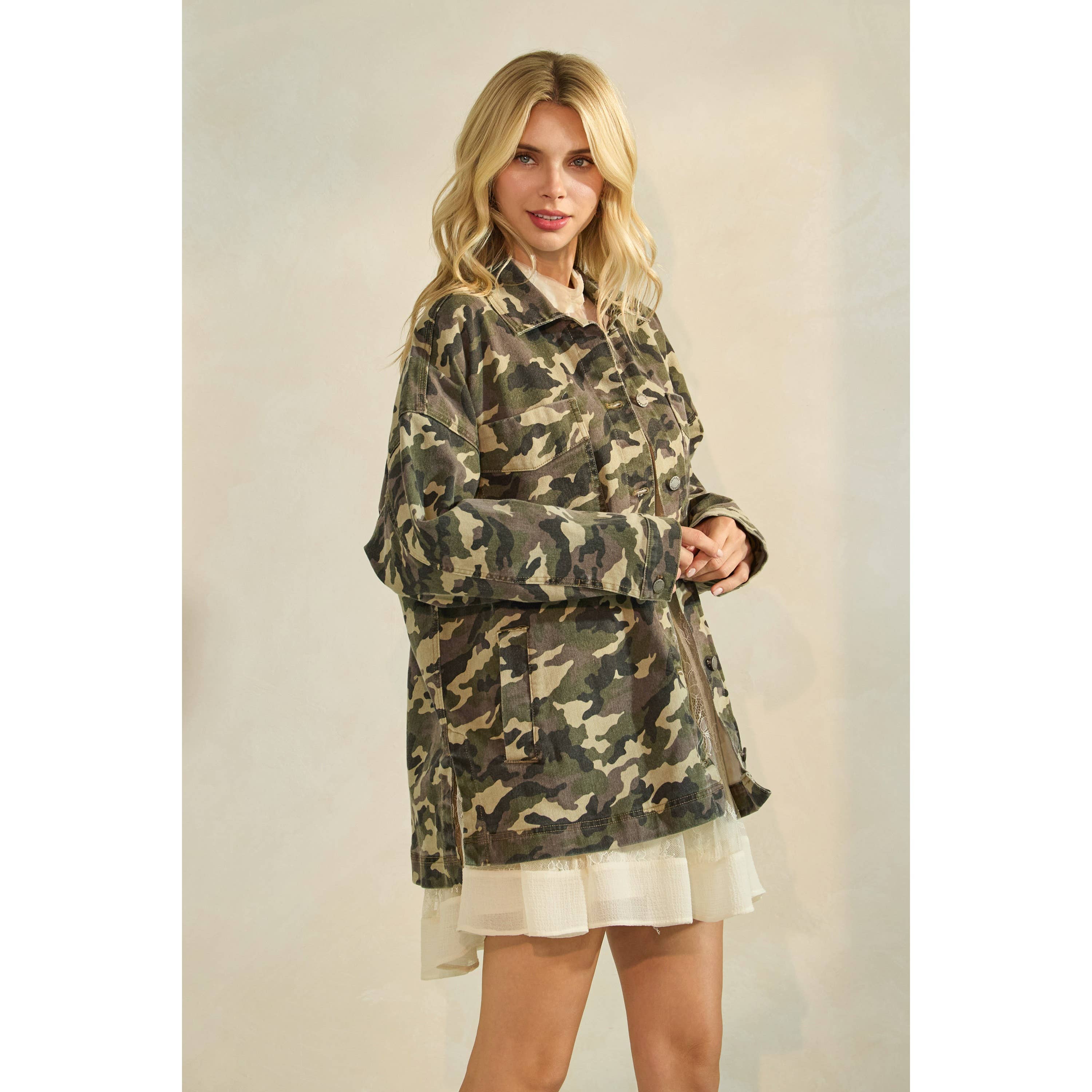 Oversized camouflage print jacket with front pockets and button closure, styled over a white tiered mini dress.