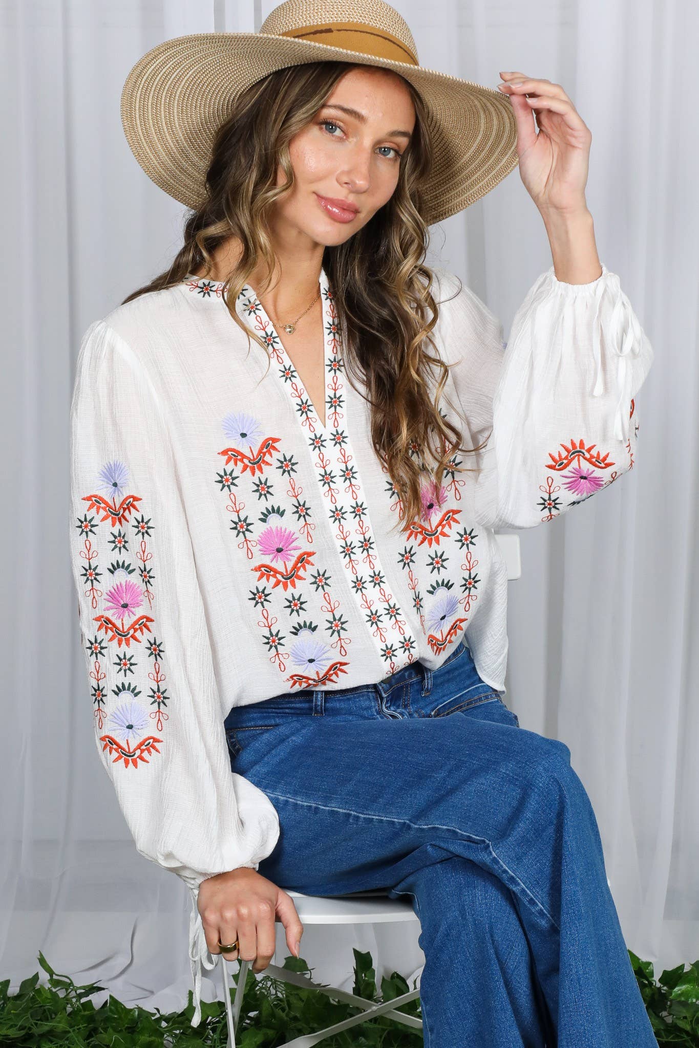White embroidered peasant blouse with multicolor floral front, split V-neck, and balloon sleeves with ties