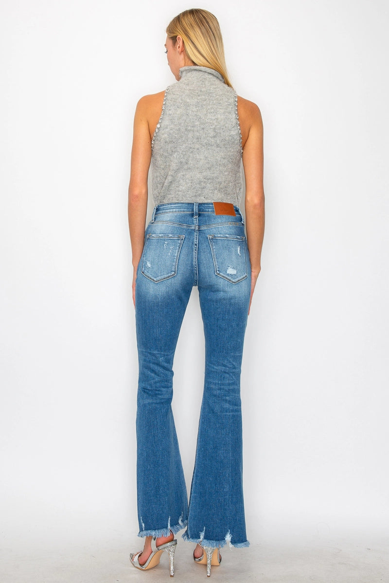 Back view — medium-wash high-rise distressed flare jeans with ripped knees, raw frayed hem, 5-pocket style on model.
