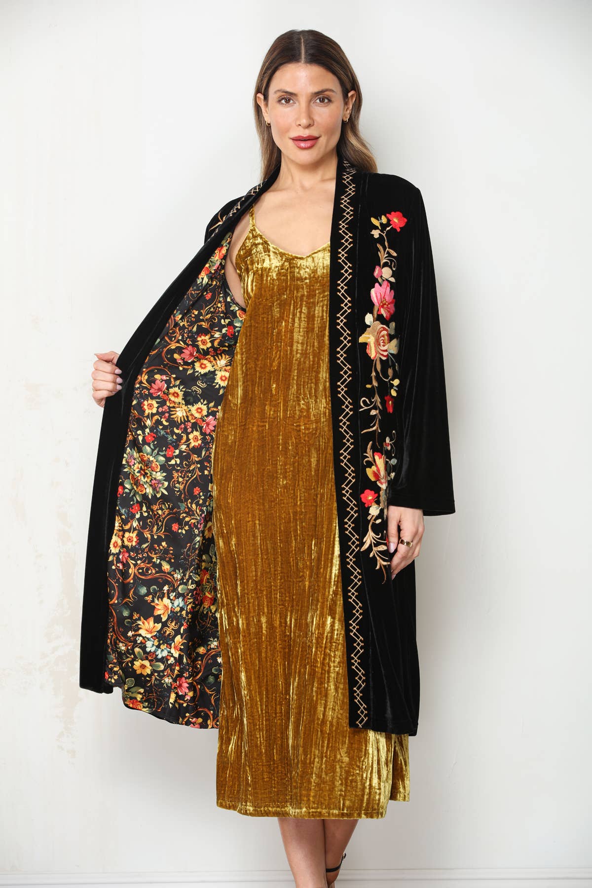 Model holding black embroidered velvet duster open to show its multicolor vintage floral printed lining.