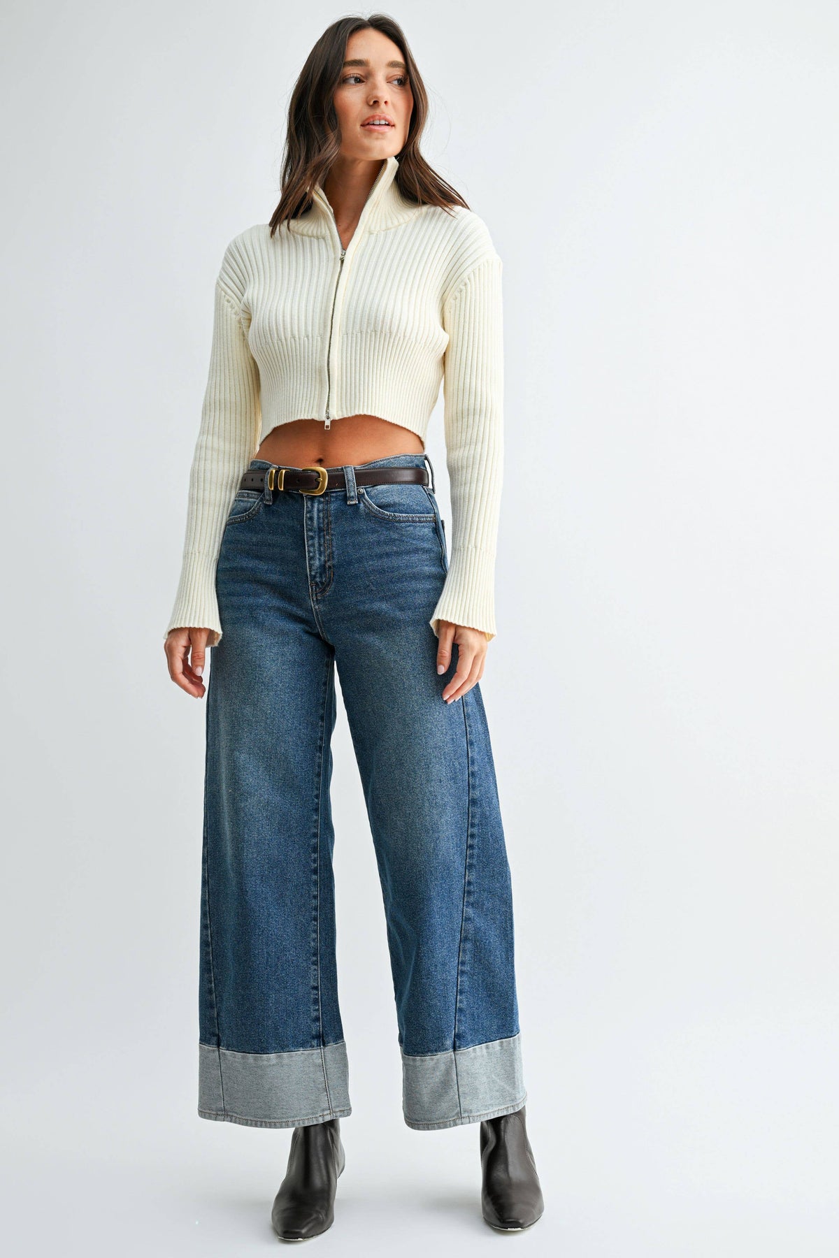 Model wearing Blue Hour Two-Tone Wide Leg Jeans with a cream cropped sweater, dark belt, and black ankle boots.