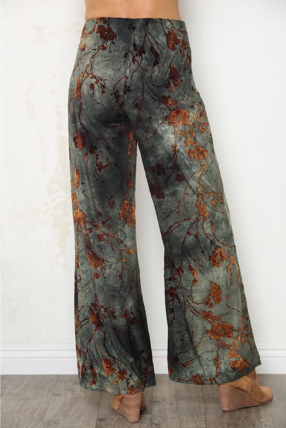 Wide-leg pants with a mottled slate gray and rust orange floral pattern, shown from the back on a model.