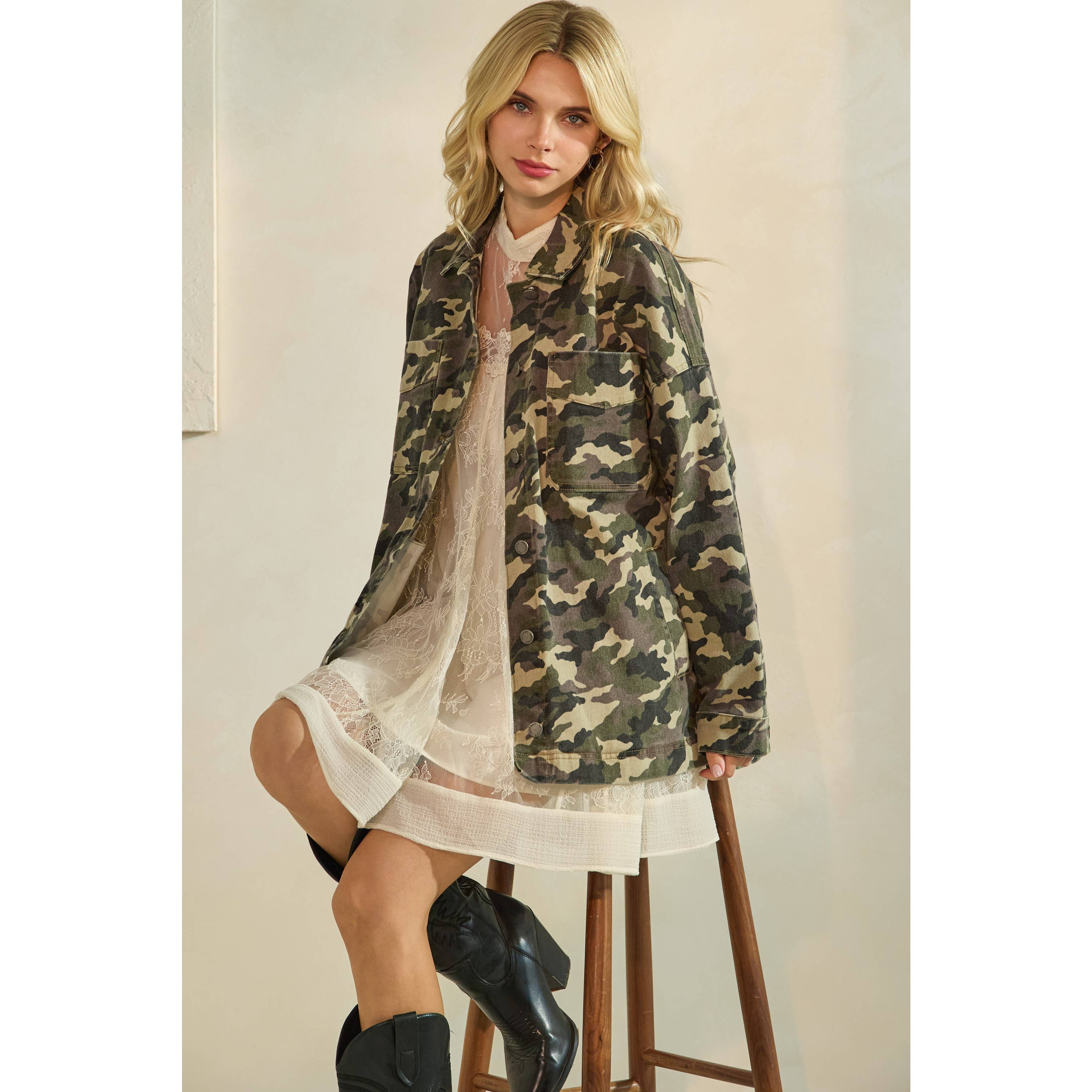 Oversized camouflage print jacket with front pockets and button closure, styled over a white tiered mini dress.