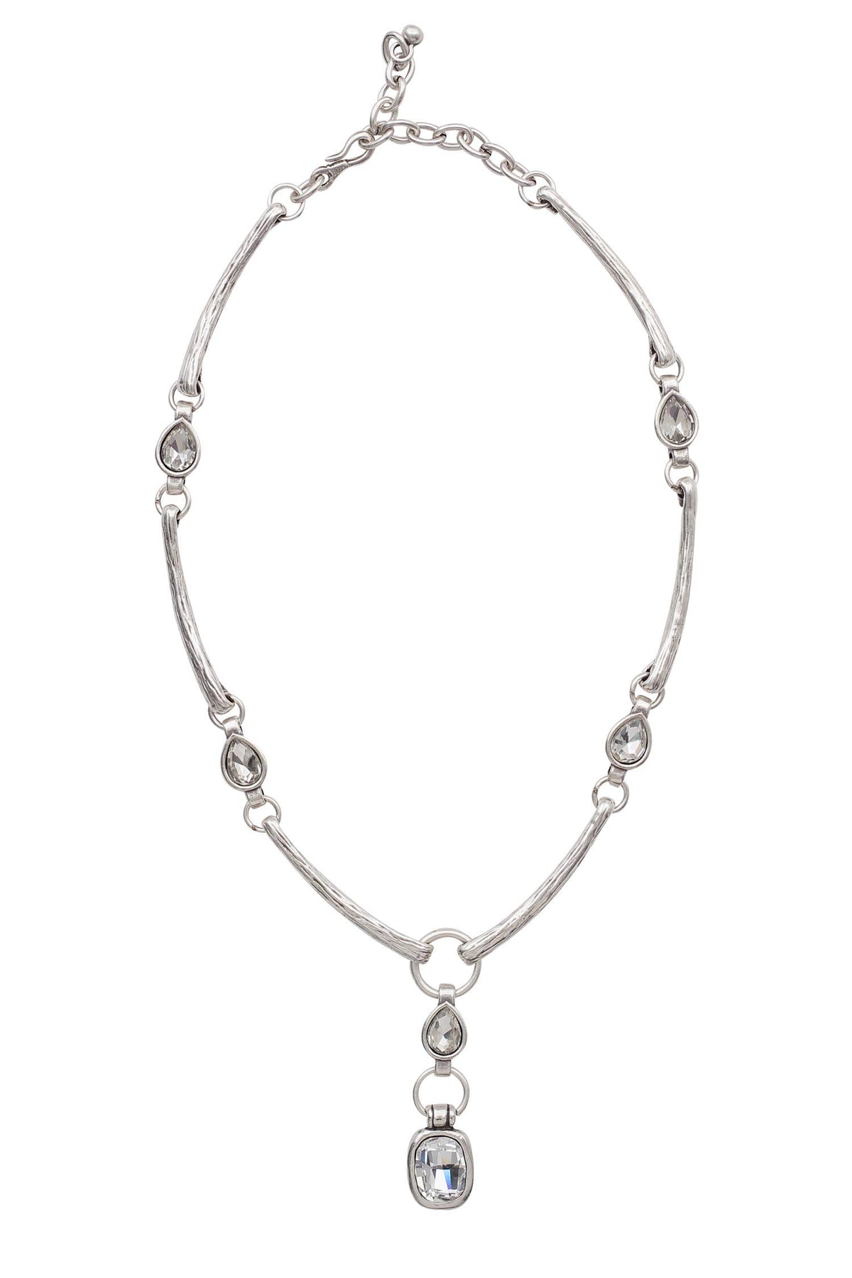 A silver-toned beaded necklace featuring a textured chain, small oval and teardrop beads, and a central hanging charm with a clear faceted gemstone, shown against a plain white background.