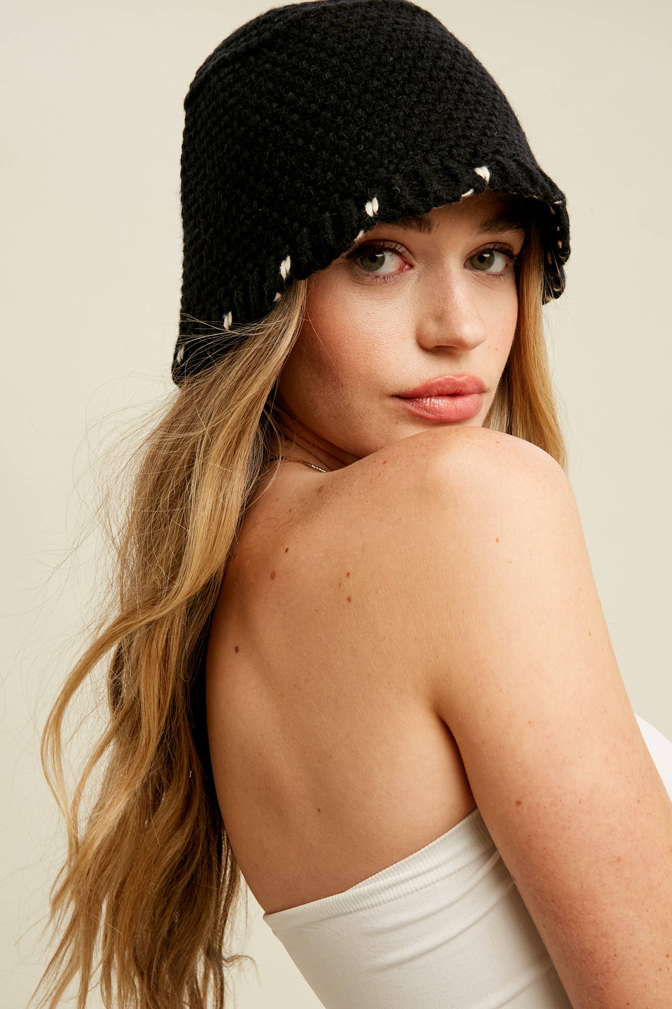 Close-up — black knit bucket hat with contrast white whipstitch trim and soft brim, on model.