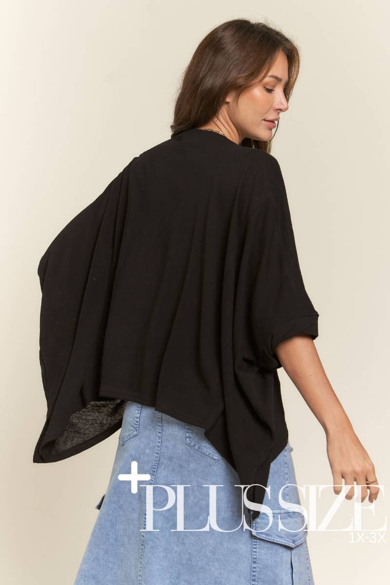 Woman wearing a black oversized top and blue jeans on a beige background with 'Plus Size' text.