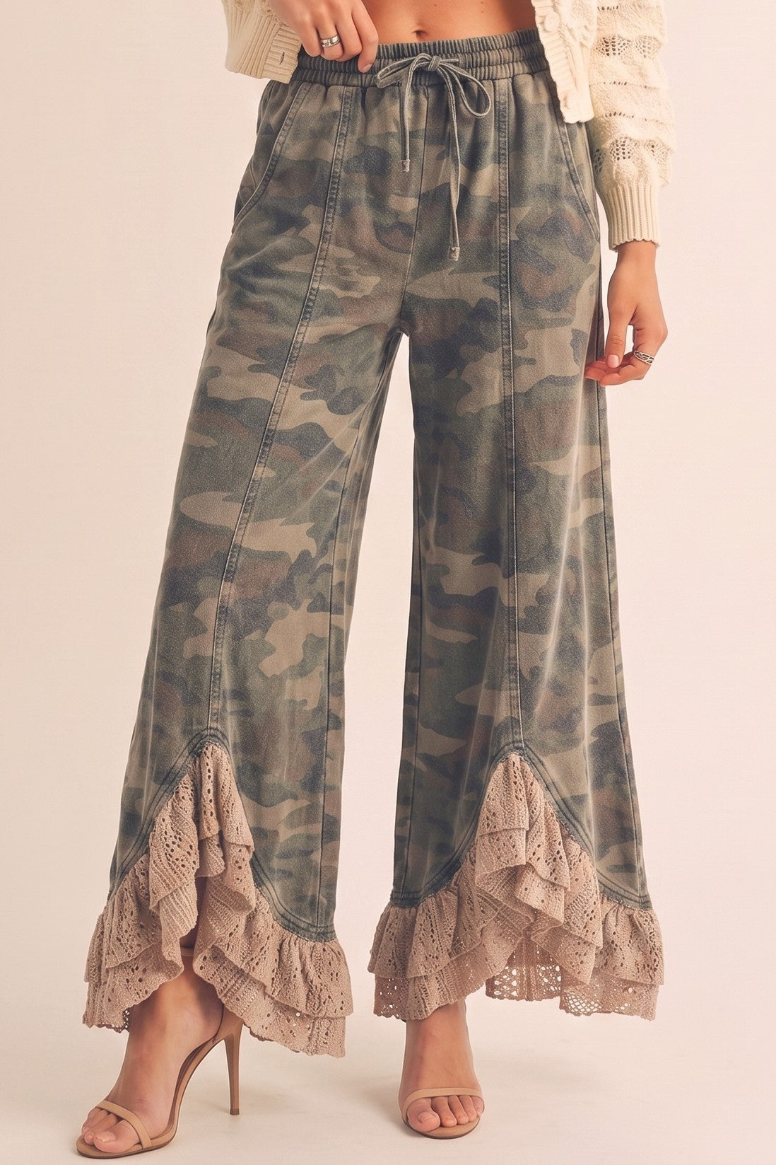 Camouflage pants with lace trim worn by a person on a plain background