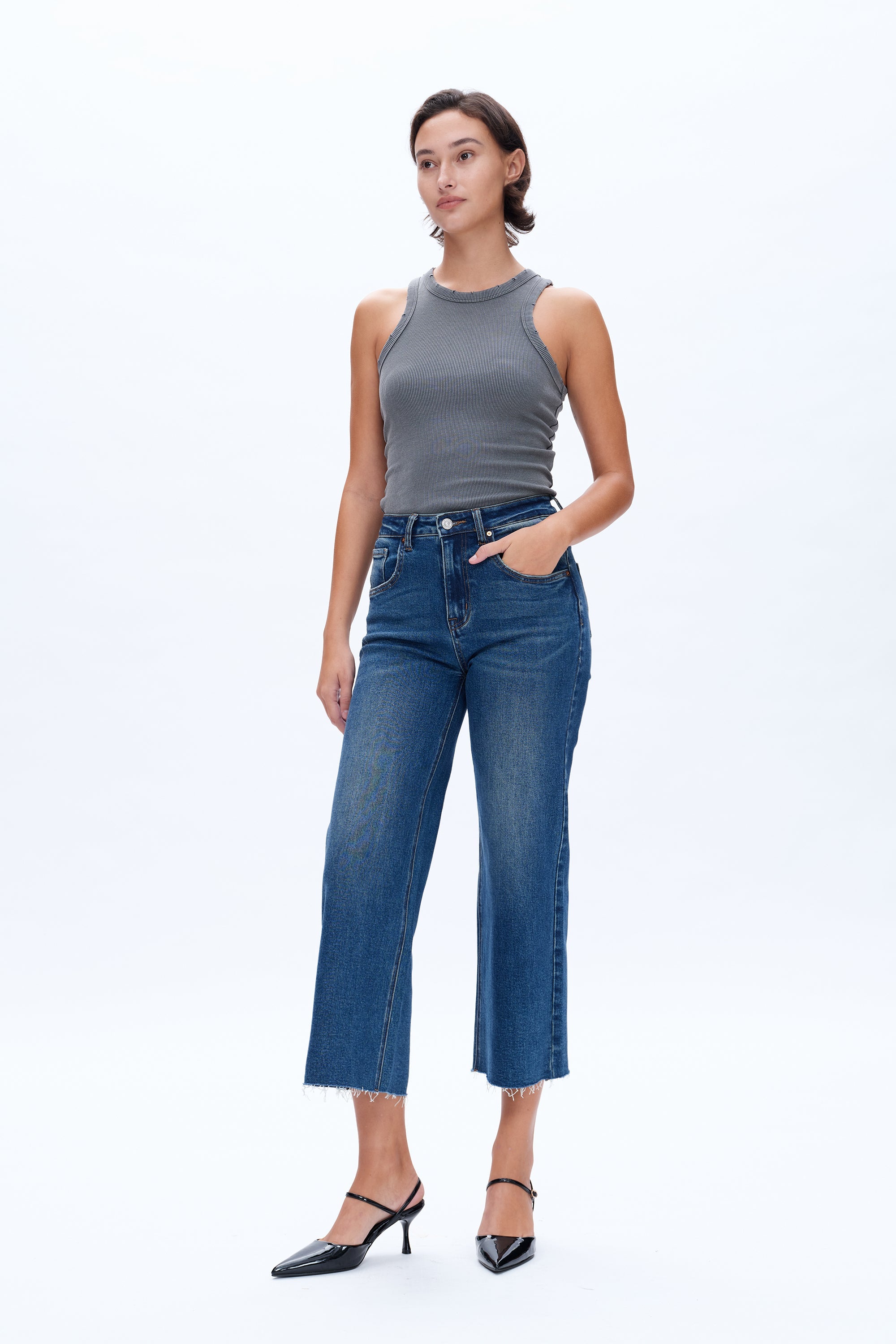 Woman wearing a gray sleeveless top and blue jeans on a white background