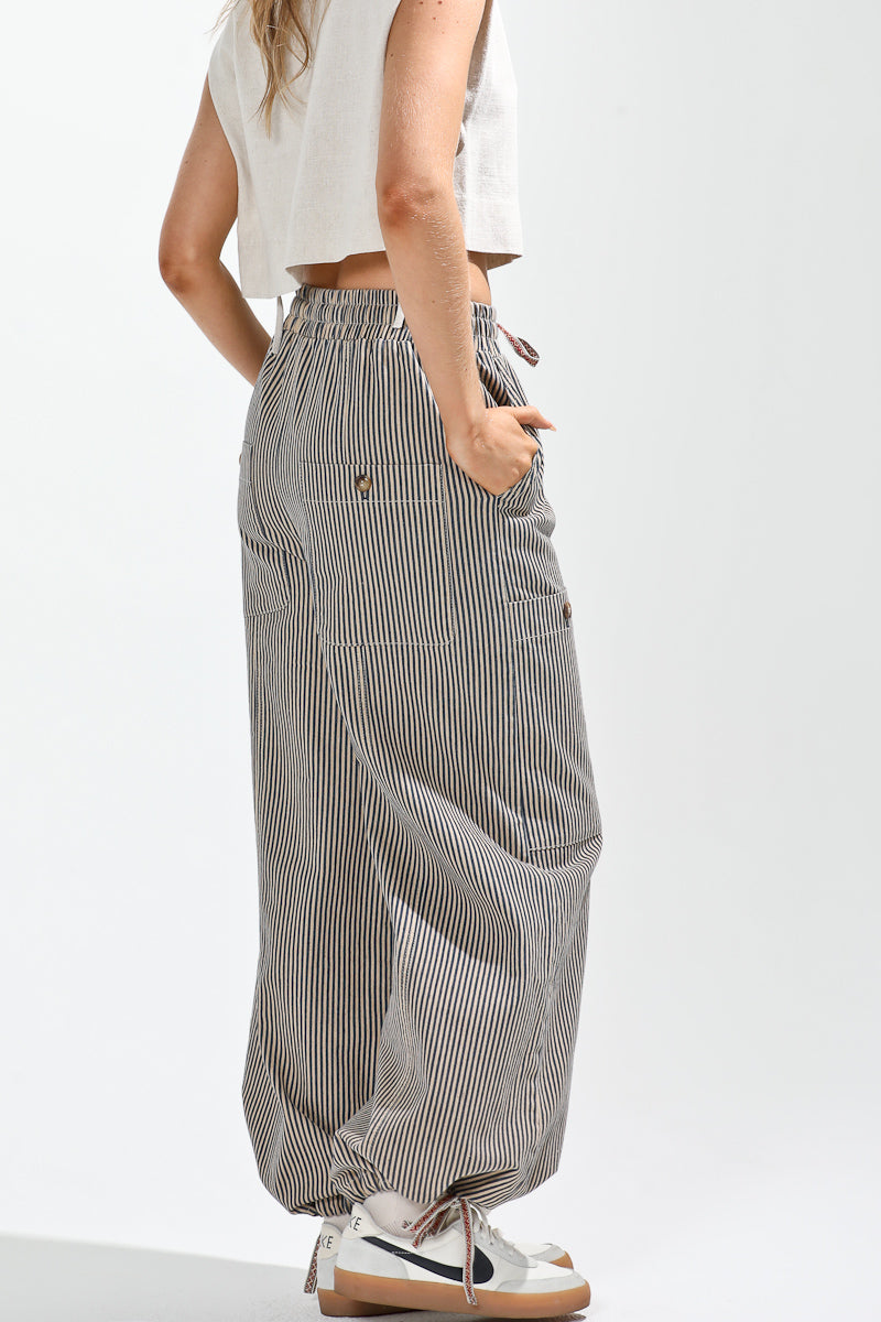 Person wearing a white top and gray striped wide-leg pants on a white background