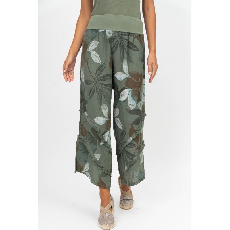 Person wearing green leaf-patterned pants on a white background