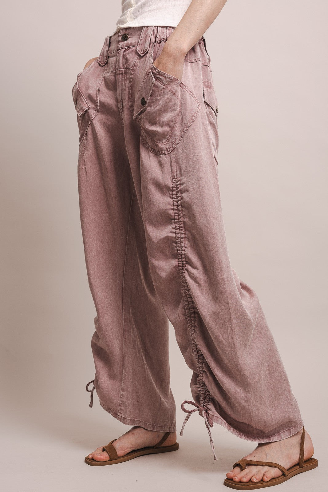 Person wearing a pair of loose-fitting, brownish pants on a plain background