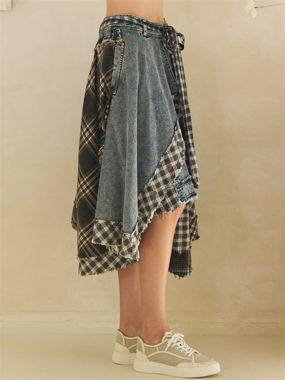 Model wearing a blue denim and plaid mixed skirt styled with a fitted top and sneakers side view
