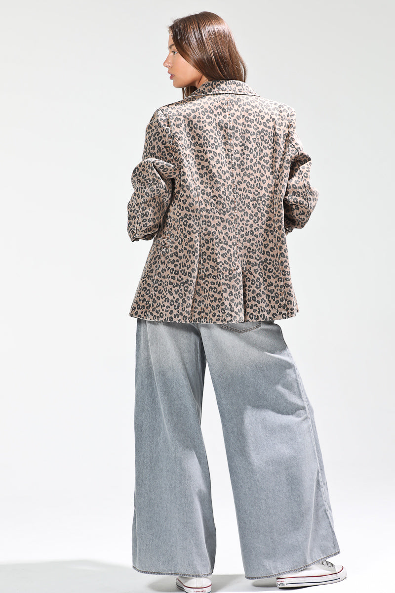 Person wearing a leopard print jacket and light blue pants on a white background