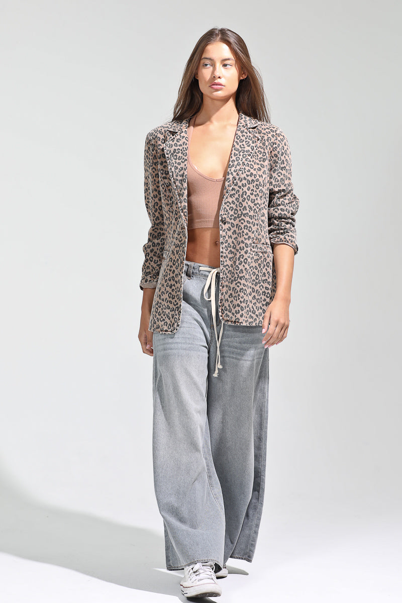 Woman wearing a leopard print cardigan, beige top, gray pants, and black sneakers on a white background