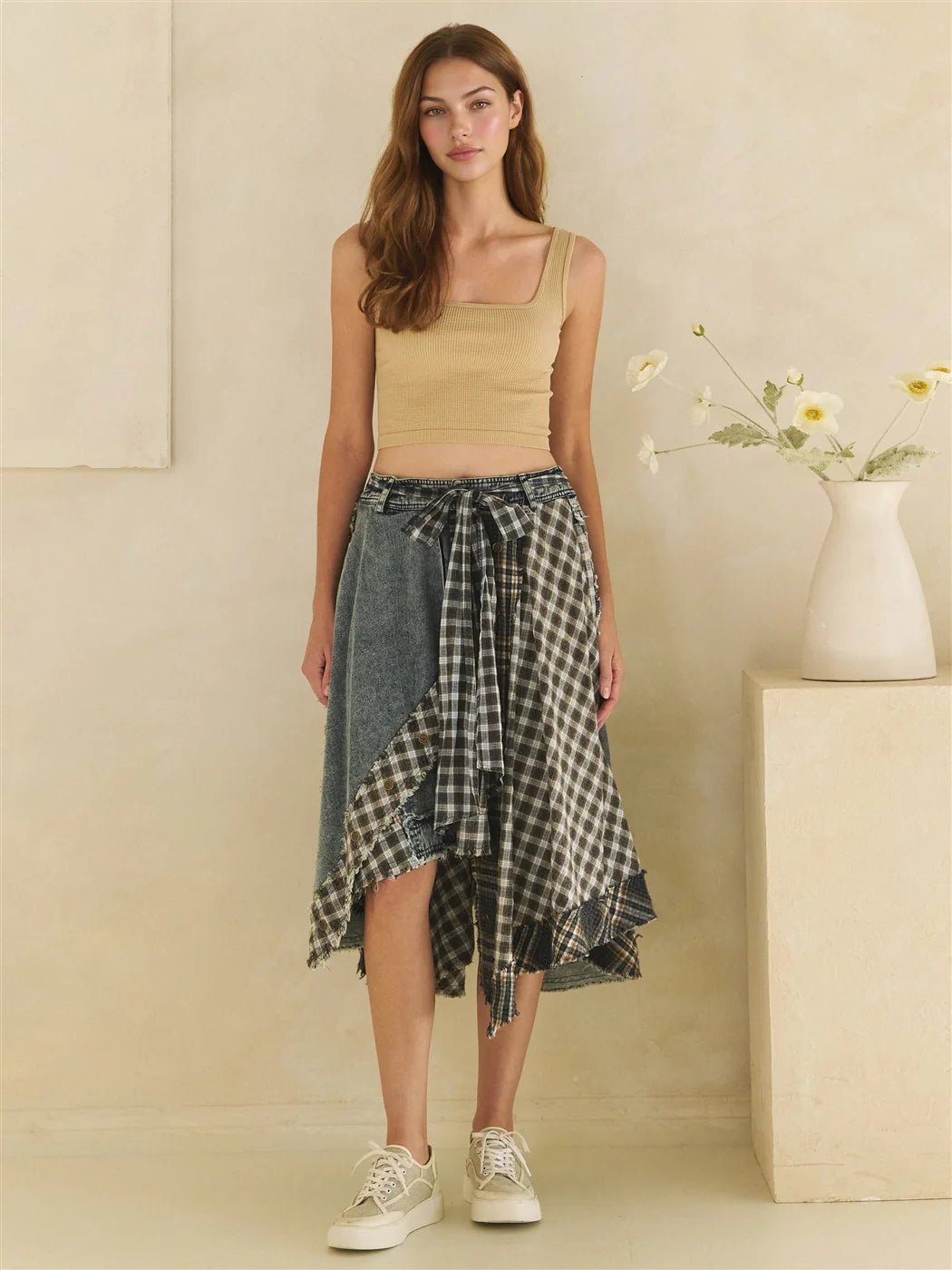 Front view of a model wearing a mixed plaid and denim asymmetrical draped skirt with a relaxed fit.
