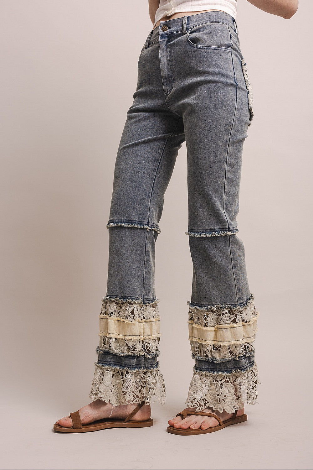 Denim pants with lace detailing on a plain background