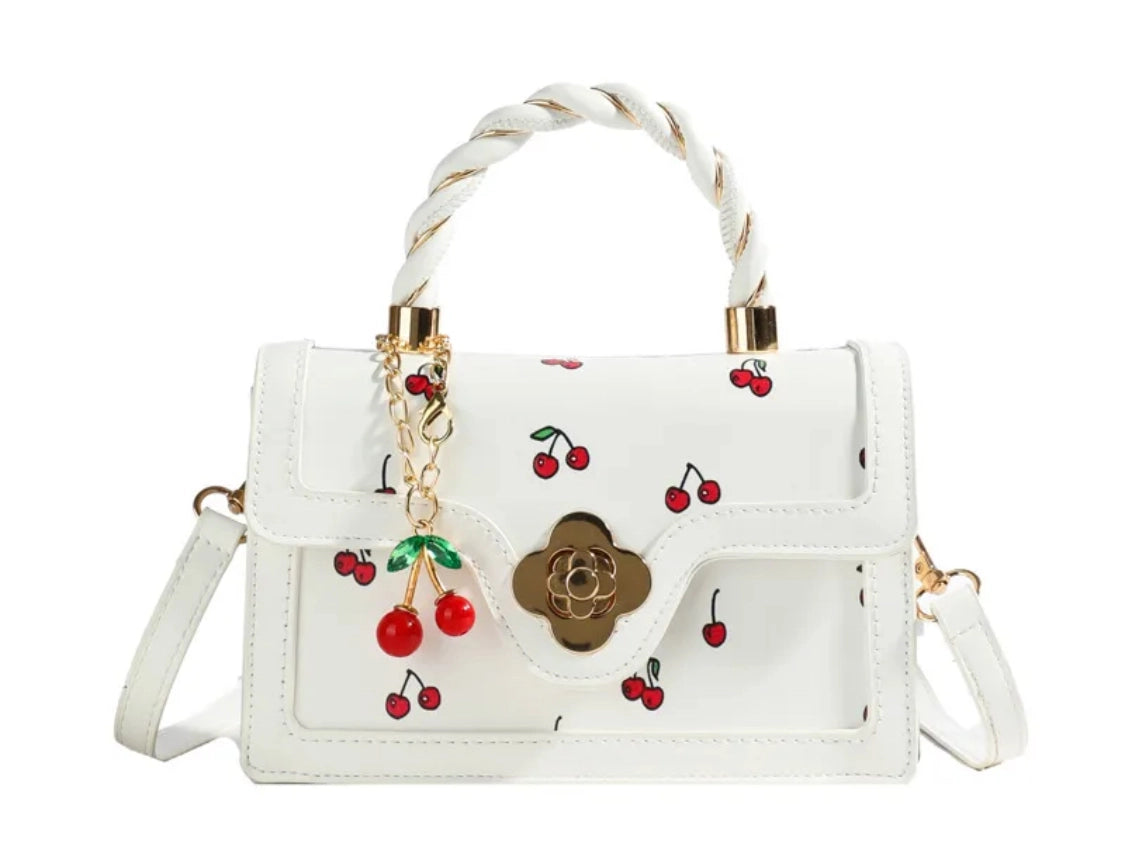 White handbag with cherry designs on a white background